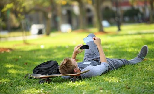 一个学生躺在草地上的滑板上